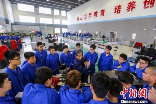 资料图：“实训工厂”内学生们正在听师傅专业讲解。　赵泉 摄